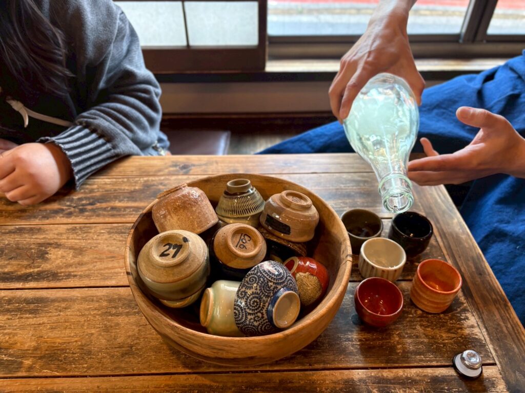 みんなで弥栄するために、日本酒をお猪口についでいるところ